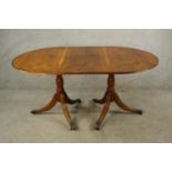 A contemporary Yew wood Regency style twin pillar dining table each pillar raised on turned