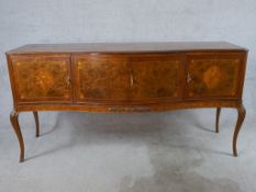 A 20th century walnut veneered serpentine fronted sideboard with four cupboard doors opening to