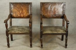 A pair of 17th century oak and leather open arm dining chairs raised on turned supports and