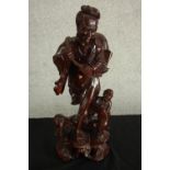 An early 20th century carved Chinese hardwood figure of a fisherman and a child, raised on
