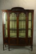 An early 20th century mahogany breakfront twin door display cabinet, with carved blind cornice and