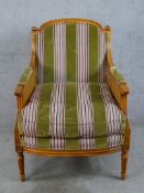 A late 19th/early 20th century walnut and bergère framed French style armchair raised on fluted