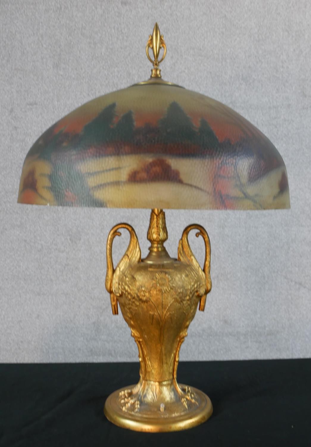 A 20th century table lamp with reverse glass painted light shade, standing on a twin swan/crane head