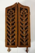 A 20th century carved Indian hardwood small two door wall hanging carved book cabinet, opening to