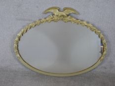 A 20th century oval gilt framed mirror mounted with leaf and eagle decoration. H.77 W.96cm
