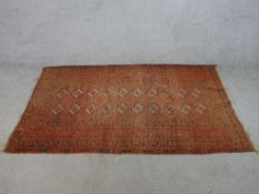 A 20th century Persian orange ground woollen rug with lozenge design within geometric border. H.