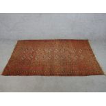 A 20th century Persian orange ground woollen rug with lozenge design within geometric border. H.