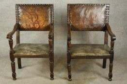 A pair of 17th century oak and leather open arm dining chairs raised on turned supports and feet.