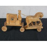 A 20th century carved hardwood toy in the form of a horse being pulling a coach, raised on wheels.