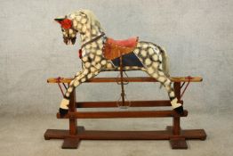 A 20th century dapple grey rocking horse with painted and fabric saddle on stripped pine cradle