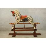 A 20th century dapple grey rocking horse with painted and fabric saddle on stripped pine cradle