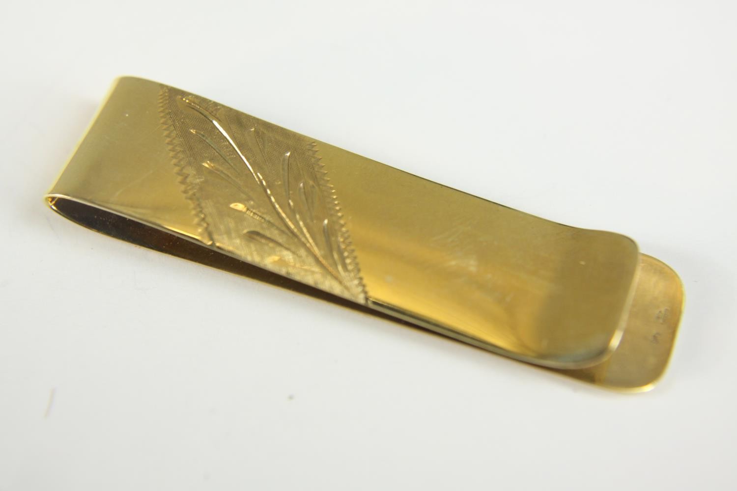 A 9ct gold engraved money clip with foliate design. Hallmarked: AG for Alfred Grove, London import