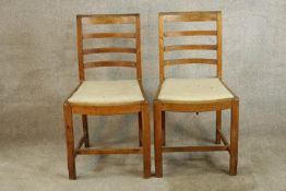 A pair of early 20th century oak framed ladder back dining chairs, raised on carved supports with