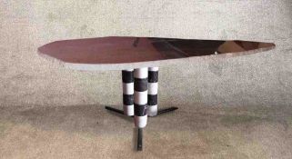 A contemporary polished granite topped table raised on three black and white marble cylindrical