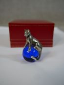 A Cartier silver and crystal Panther paperweight, the sterling silver Panther seated on a blue glass