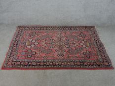 A 20th century red ground woollen rug with all over floral pattern. H.104 W.148cm