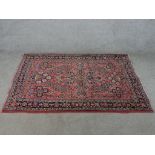 A 20th century red ground woollen rug with all over floral pattern. H.104 W.148cm