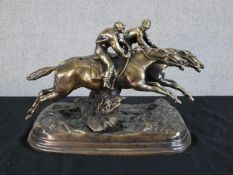 A 20th century cast brass model of two race horses and jockeys raised on shaped plinth base. H.17