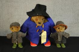 A 20th century standing Paddington Bear with gum boots, together with two 20th century clothed teddy