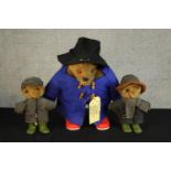 A 20th century standing Paddington Bear with gum boots, together with two 20th century clothed teddy