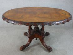 A 19th century carved walnut oval topped tilt dining table raised on turned supports terminating