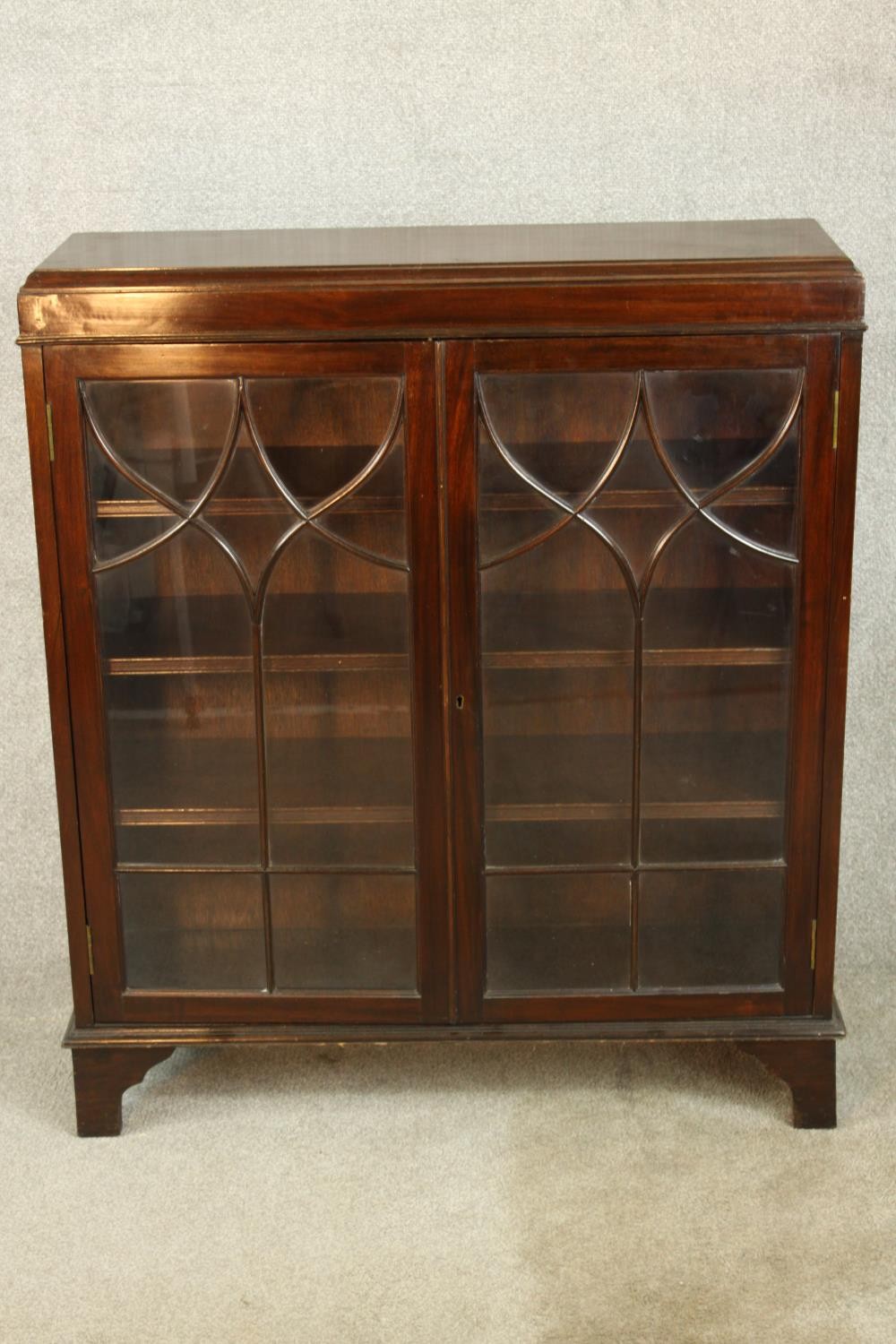 An early 20th century mahogany two door door display cabinet raised on shaped bracket feet. H.107 W.