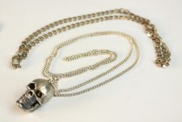 Two silver chains. A silver skull pendant with articulated jaw when opened reveals cubic zirconia