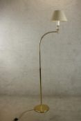 A contemporary brass floor standing lamp with adustable arm raised on circular foot. H.184cm.