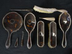 An Art Deco silver and tortoiseshell dressing table set along with a silver repousse floral design