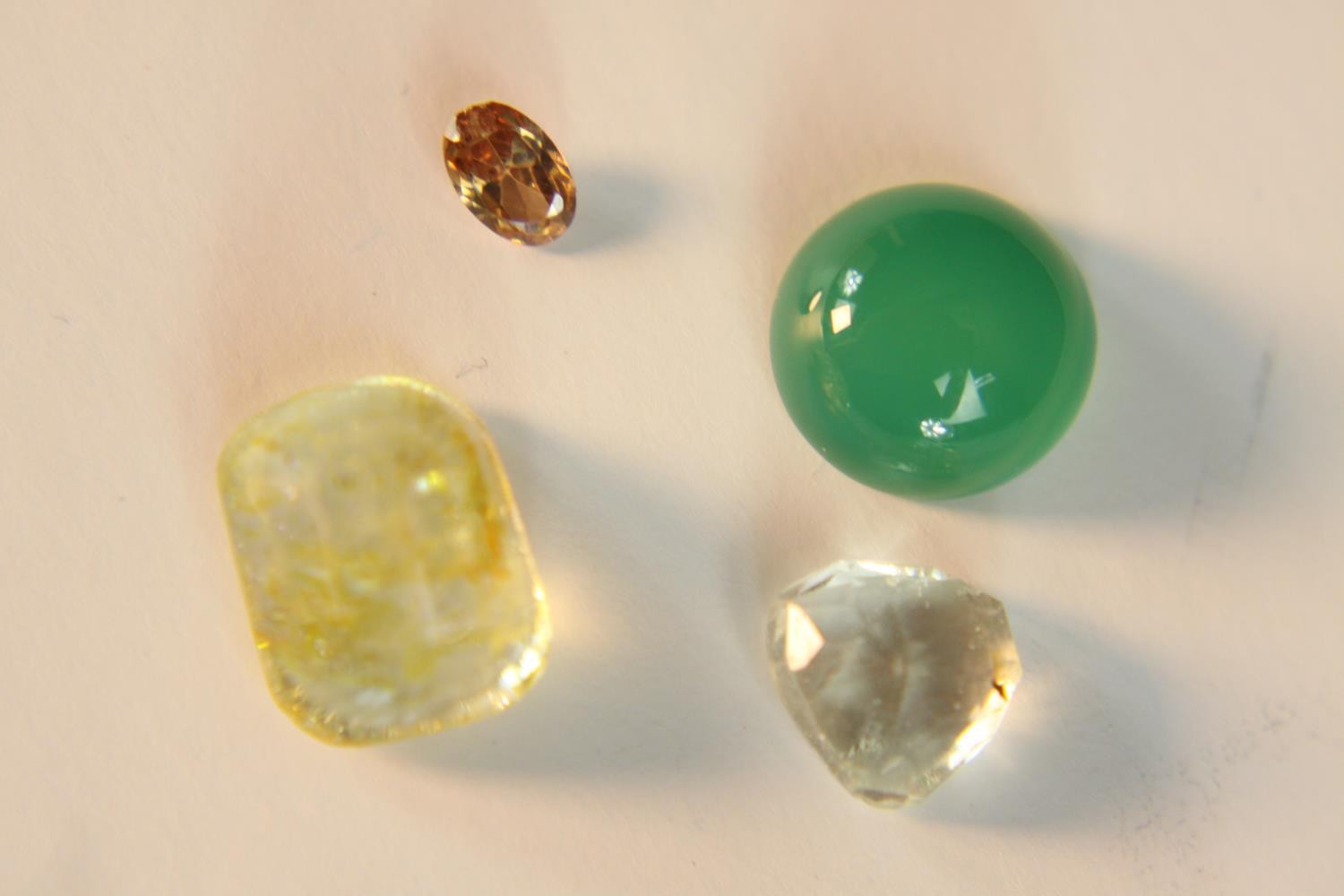 A collection of mixed cut loose gemstones, including a round cabochon Chrysoprase and rock crystal.