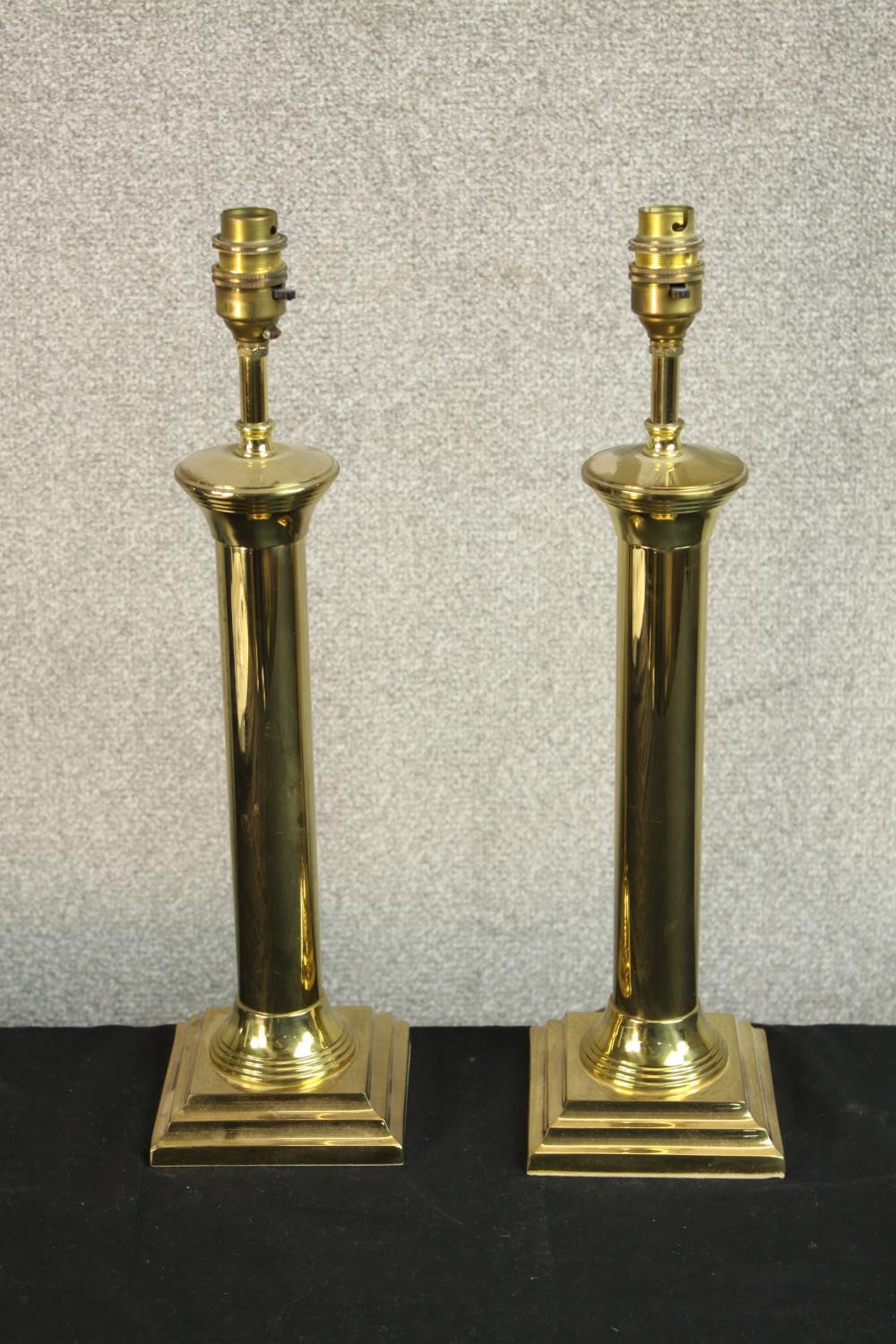 A pair of 20th century brass cylindrical table lamps raised on stepped square bases. H.44cm.