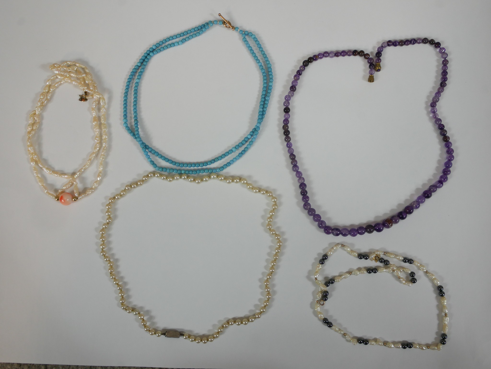 A collection of five vintage necklaces, including an amethyst graduated bead necklace, two sets of