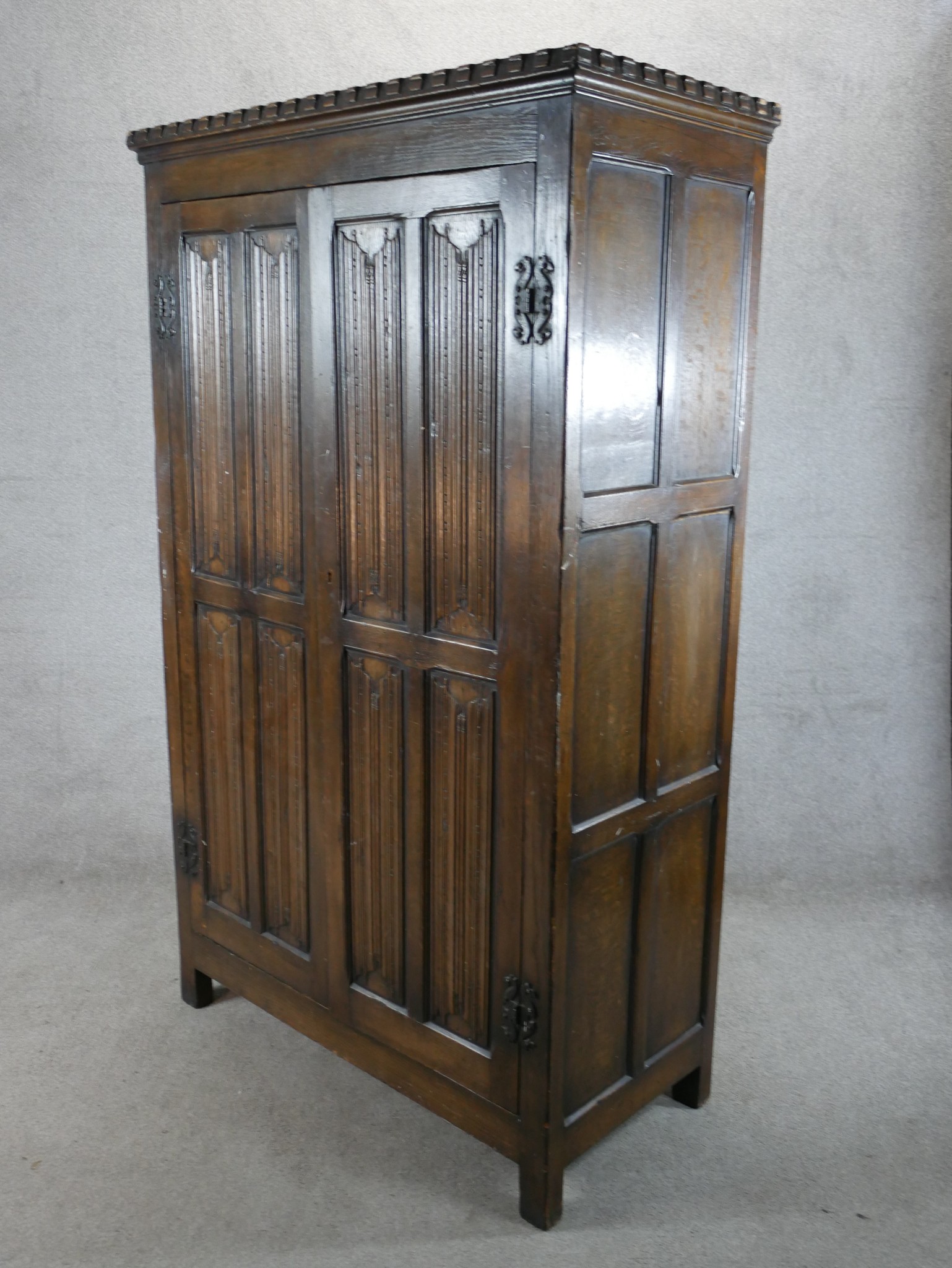 A 20th century stained oak twin door wardrobe with panels of linen fold decoration raised on - Image 4 of 5