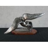 An Art Deco style pewter model model of a flying bird raised on oval mahogany oval plinth. H.32 W.60