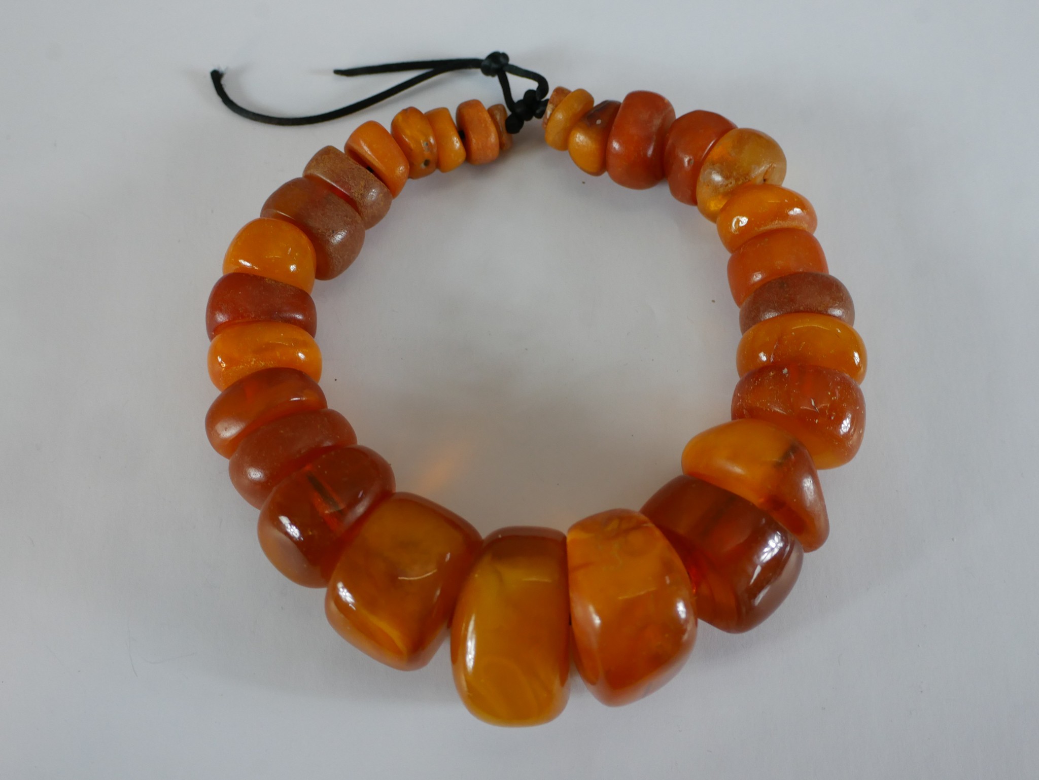 A string of twenty nine graduated African amber beads, the largest bead measuring 4.4cm in length by