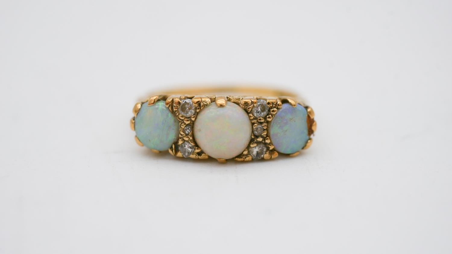 A vintage three stone carved half hoop 18 carat yellow gold opal and diamond ring. Set with three