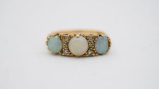 A vintage three stone carved half hoop 18 carat yellow gold opal and diamond ring. Set with three