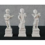 Three 19th century white glazed porcelain figures of cherubs playing musical instruments raised on