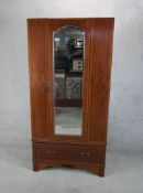 An Edwardian inlaid mahogany mirror single door wardrobe raised on single drawer on shaped bracket