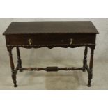An early 20th century oak single drawer side table with brass swing handles, raised turned