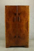 An early 20th century walnut veneered two door wardrobe, the twin doors opening to reveal hanging