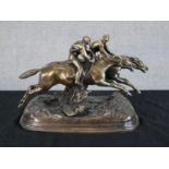 A 20th century cast brass model of two race horses and jockeys raised on shaped plinth base. H.17