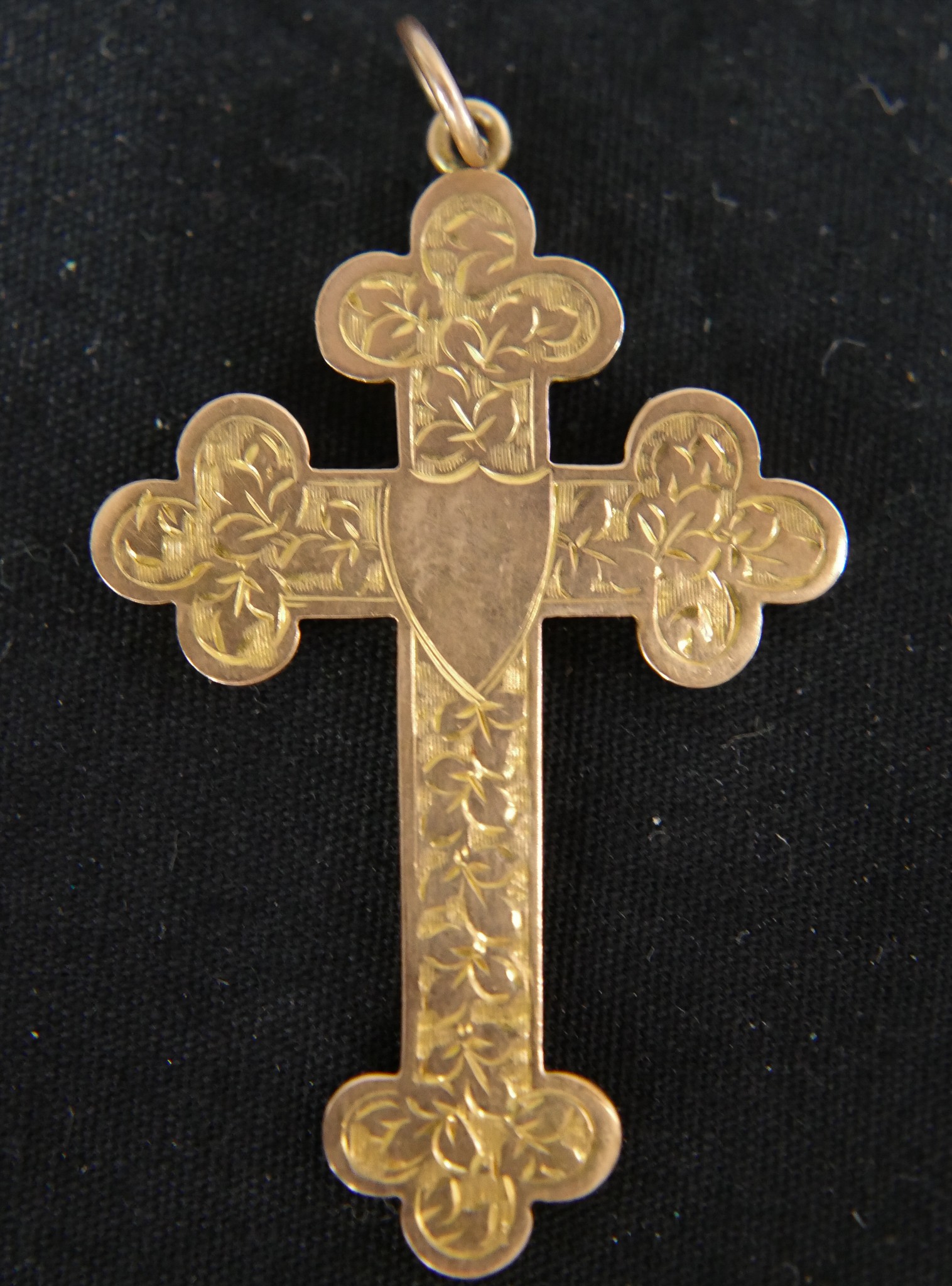 A 9ct rose gold engraved cross with shield shaped cartouche in the centre. Hallmarked: AJ,