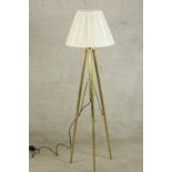 A contemporary brass floor standing lamp raised on three splayed supports. H.138cm.