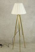 A contemporary brass floor standing lamp raised on three splayed supports. H.138cm.