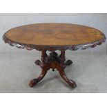 A 19th century carved walnut oval topped tilt dining table raised on turned supports terminating