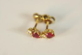 A pair of yellow metal (tested higher than 9ct) diamond and ruby stud earrings, set to top with a