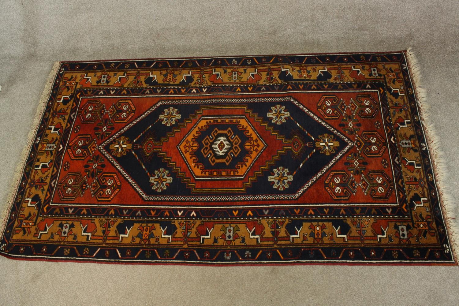 A 20th century red and blue ground Persian woollen rug with all over geometric pattern. L.210 W.