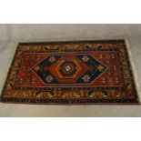 A 20th century red and blue ground Persian woollen rug with all over geometric pattern. L.210 W.