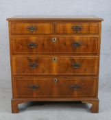 A George III style crossbanded walnut chest of two short over three graduating drawers with brass